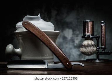 Shaving razors and bowl with foam on wooden background 