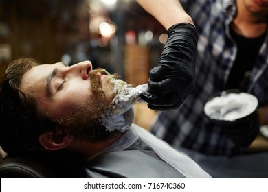 Shaving ritual in barbershop - barber applying foam before procedure