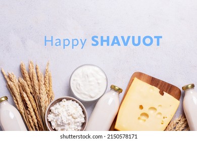 Shavuot flat lay with dairy products and wheat on light gray background, Happy Shavuot text. Jewish Shavuot holiday frame with dairy foods and quote happy Shavuot, top view