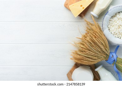 Shavuot jewish holiday celebration. Milk and cheese, ripe wheat and fruits, cream on white wooden background. Dairy products over white wooden background. Shavuot concept. Top view. Mock up.