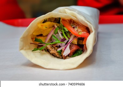 Shawarma meat chicken roll in a pita with fresh vegetables. 
