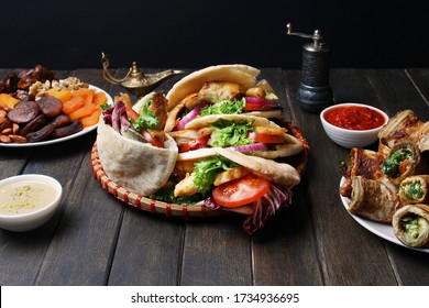 Shawarma In Pita Flat Bread On Black Wooden Table With Tahini And Harissa Sauces. Ramadan Food Concept. Side View.