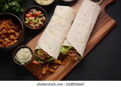 Shawarma Rolled Sandwich With Sauce And Vegetables, Arab Traditional Food. Shawarma Doner Kebab Wrap With Chicken, Fries And Pickles. Israeli Traditional Homemade Shawarma On Wooden Cutting Board.