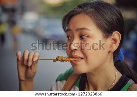 she eating spicy barbecue at market