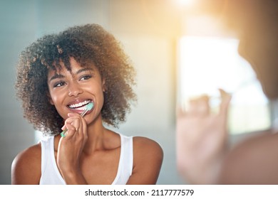 She enjoys oral hygiene. Cropped shot of a young woman brushing her teeth in the bathroom. - Powered by Shutterstock