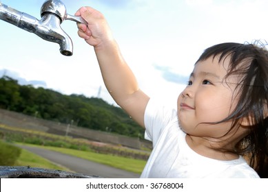 She is a happy baby washing her hand and turn off faucet in the outdoor.