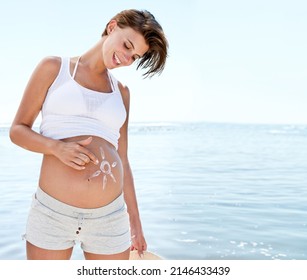 She has a sunny tummy. Shot of a beautiful pregnant woman with the sun drawn onto her belly against the background of the ocean. - Powered by Shutterstock