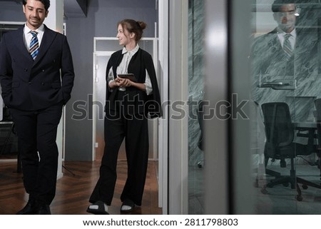 She looks up at him to drive the idea home as their steps continue, the corridor around them washed in low golden light and shadow in a bright modern coworking office.