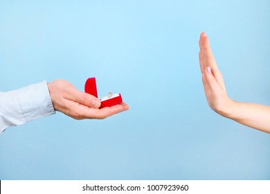 She Said NO Concept. Young Girl Rejects The Marriage Proposal. Woman Refuses The Engagement Gold Platinum Diamond Ring, Man Male & Female Hands Close Up, NO Gesture. Blue Background, Copy Text Space.