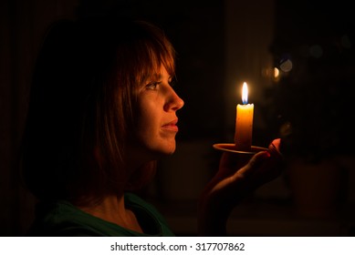 She shines a candle in a dark room