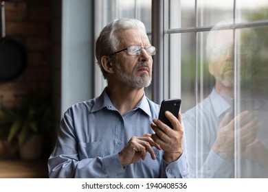 She should be back by now. Worried older man husband look at window wait for wife delayed to go back home hold phone make call. Nervous retired father feel distressed for grown child dial cell number - Powered by Shutterstock