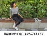 She sits outside on a park bench, enjoying the fresh spring air. With a relaxed posture, she closes her eyes and takes a deep breath raising her head upward.
