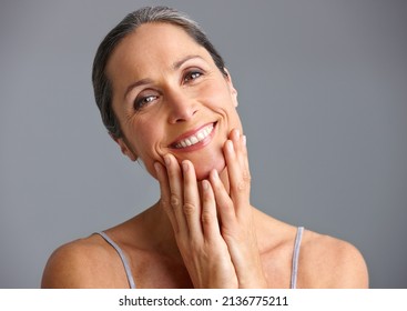 She takes good care of her skin. Studio portrait of a beautiful mature woman posing against a gray background. - Shutterstock ID 2136775211