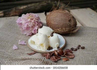                       Shea Butter With Coconut Nut, Nut Shells, Coffee Beans And Pink Flower On A Beige, Linen Or Hemp Canvas And Wooden Background.         