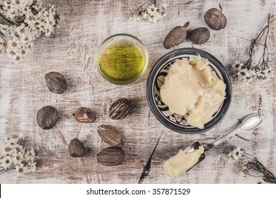 Shea Butter, Oil And Nuts On A Shabby White Table With White Flower And Silver Spoon