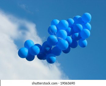 Sheaf of blue party balloons against the cloudy blue sky