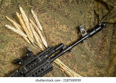 A Sheaf Of Wheat Grain Against The Background Of Russian Digital Pixel Camouflage With A Automatic Rifle. The Concept Of World Hunger.