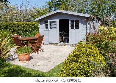 Shed With Open Door And Terrace With Wooden Garden Furniture During Spring