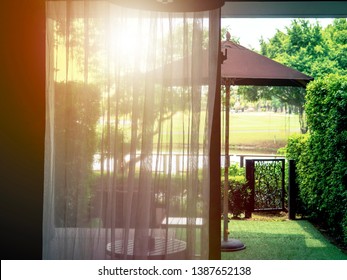 Sheer curtain in room closed half way in sunset time and sun shine through from balcony of outdoor garden backyard. - Powered by Shutterstock