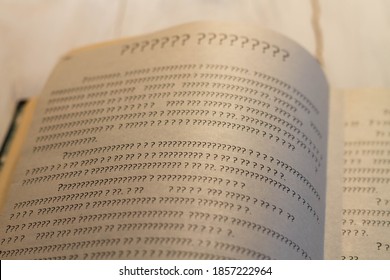 A sheet of book with question marks on the page. The book is open, but there is not a single letter.