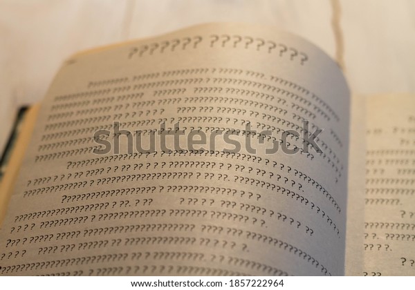 A sheet of book with\
question marks on the page. The book is open, but there is not a\
single letter.