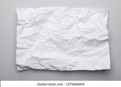 Sheet of crumpled paper on grey background, top view