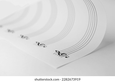 Sheet with empty staves for music notes and treble clef on white background, closeup