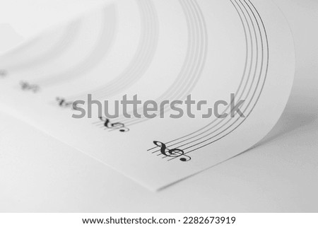 Sheet with empty staves for music notes and treble clef on white background, closeup