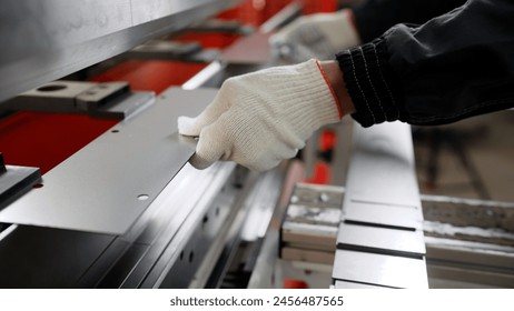 Sheet metal bending in factory. Sheet metal on a machine. Worker in factory at metal skip machine putting work piece in. Man working with sheet metal and special machine tools for bending.  - Powered by Shutterstock