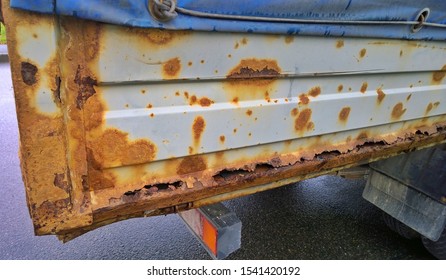 Sheet Metal Corrosion Of Body Of An Old Truck. Rusty Surface, Background And Damaged Texture From Road Salt And Reagents. Protection And Professional Paintwork Concept. Dirty Cargo Bed. 
