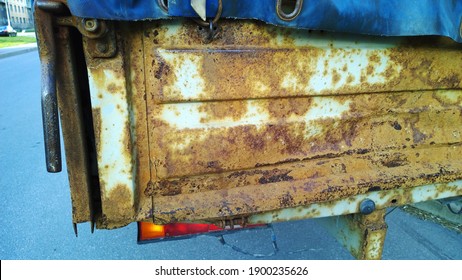 Sheet Metal Corrosion Of Body Of An Old Abandoned Truck. Rusty Surface, Background And Damaged Texture From Road Salt And Reagents. Protection And Professional Paintwork Concept. Dirty Cargo Bed.