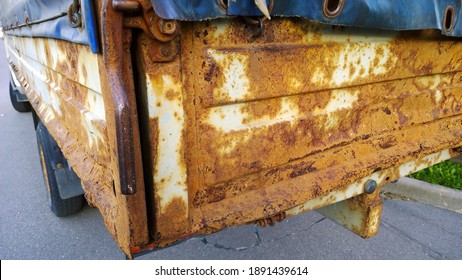 Sheet Metal Corrosion Of Old Truck Body. Rusty Surface, Background And Damaged Texture From Road Salt And Reagents. Protection Car And Professional Paint Work Concept. Messy Dirty Rust Cargo Bed.