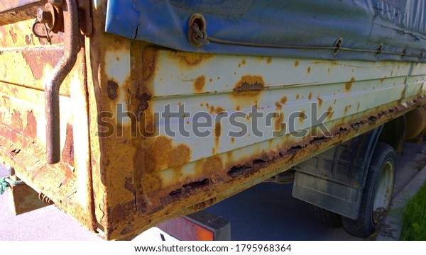Sheet metal corrosion of old truck body. Rusty surface,\
background and damaged texture from road salt and reagents.\
Protection car and Professional paint work concept. Messy dirty\
rust Cargo bed. 