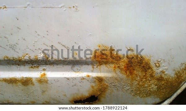 Sheet metal corrosion of\
an old white car. Rusty messy surface. Damaged grunge texture from\
road salt. Rust background. Protecting the automobile concept. Copy\
space.