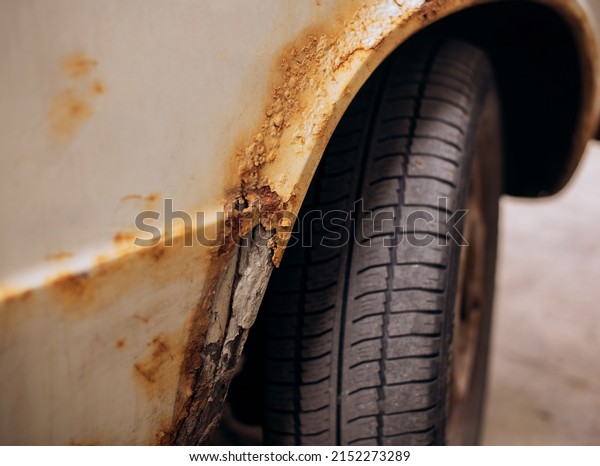 Sheet metal corrosion over wheel of\
old white car. Rusty messy surface. Damaged grunge dirty texture.\
Rust background. Protecting automobile\
concept.