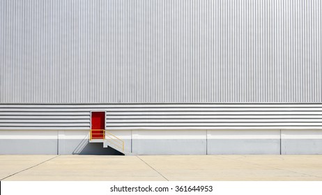 The Sheet Metal Factory Wall With The Red  Entrance Door In The Industrial Park.The Red Door Of The Factory Building.