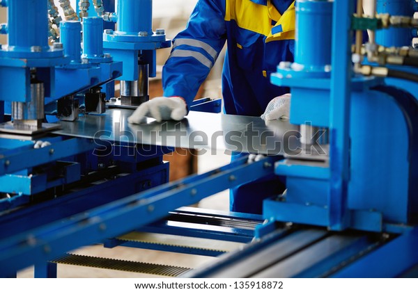 Sheet of\
metal and hands of worker who works on\
press