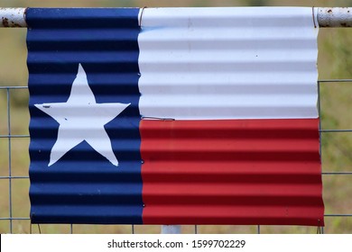 Sheet Metal Texas Flag On A Fence In Front Of An Abandoned House In Rural South Texas