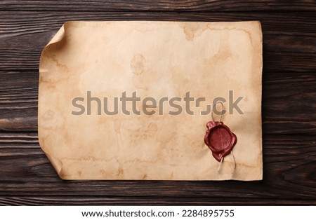 Sheet of old parchment paper with wax stamp on wooden table, top view. Space for text