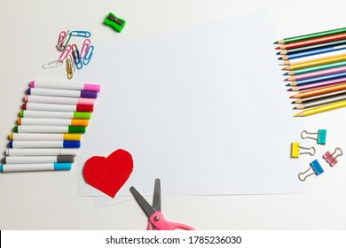 Sheet Of Paper, Crayons, Pencils, Scissors And Supplies On A White Table. Children's Art, Craft For Kids Or Preparing A Child For School. Desktop For Creativity