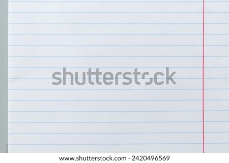 Sheet of school exercise book or paper notebook lined with light blue lines and margin are marked with a red line, top view