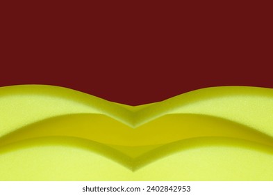 sheet of thin yellow sponge foam material on dark red background. creative foam with copy space