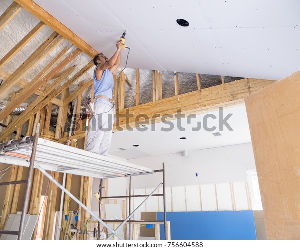 Sheetrocker Drilling Screws Into Cathedral Ceiling Stock Photo