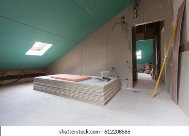 Sheets of drywall, parts of scaffolding, handle tools and construction material in the room of apartment during on the remodeling, renovation and construction