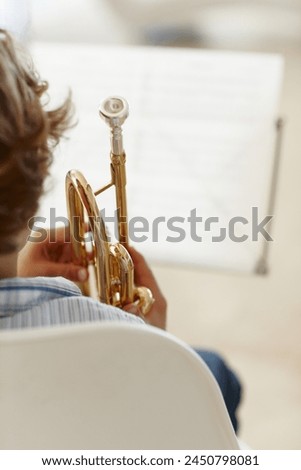 Sheets, music and child with trumpet for learning, jazz lesson and practice for talent show. Musician, creative hobby and excited young boy with instrument, paper and home to play song or melody
