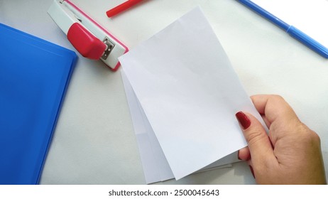 Sheets of paper in a woman's hand. Folder, stapler, paper on the table. The concept of the population census. Training.