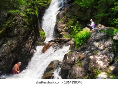 Sheffield, Massachusetts. June 22. 2019.  A Man Swimming At The Base Of Campbell Falls While A Chinese Woman Sits Watching In The Berkshires Of Western Massachusetts On A Summer Day. 