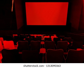 SHEFFIELD, UK - FEBRUARY 14, 2019: Blank screen and rows of generously proportioned, large modern seats in a screen room at The Light cinema, with striking red lighting