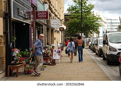 Sheffield, UK - September 12, 2019: People Were Walking Past A Bunch Of Shops In Sheffield City Centre. A Flower Shop, Barbershops, An Optician Shop Are On A Busy Street.