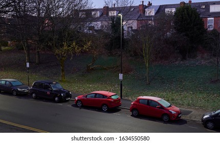 Sheffield, Yorkshire / GB - January 19, 2020: Frost-covered Cars At Dawn Parked In Suburban Street While Lit By Sky And Street Lights.